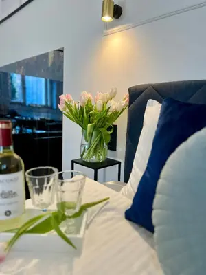 a vase of flowers on a table with a bottle of wine at Krakow Old Town Apartment Jacuzzi - wymeldowanie do 13 in Kraków