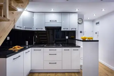 a kitchen with white cabinets and a clock on the wall at Cozy Stay Apartment - Kazimierz in Kraków