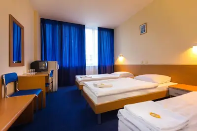 a hotel room with three beds and a television at Dom Turystyczny Indigo in Kraków