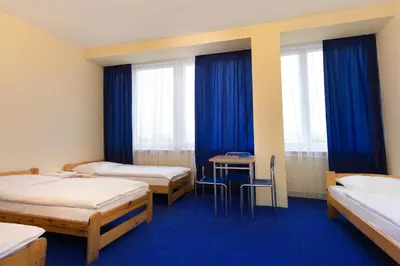 a room with two beds and a table with chairs at Dom Turystyczny Indigo in Kraków