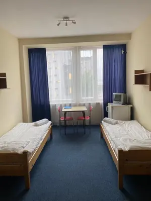 a room with two beds and a table and a window at Dom Turystyczny Indigo in Kraków