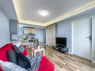 a living room with a red couch and a kitchen at Apartament z widokiem na panoramę miasta in Kraków