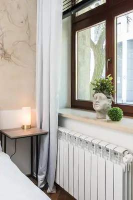 a bedroom with a radiator and a window with a candle at Urok Centrum: Podwójne Piękno in Kraków