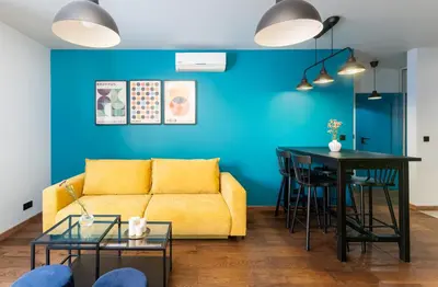 a living room with a yellow couch and a blue wall at Modern Apartments with FREE parking spots in Kraków