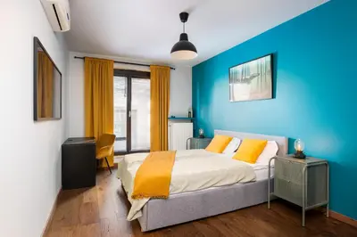 a bedroom with blue walls and a bed with orange pillows at Modern Apartments with FREE parking spots in Kraków