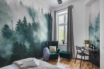 a bedroom with a large painting of trees on the wall at Copernicus House in Kraków