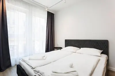 a bedroom with a bed with white sheets and a window at City of the Kings- Szafir in Kraków