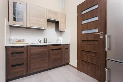 a kitchen with wooden cabinets and a door at Luxor in Kraków