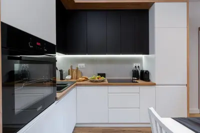 a kitchen with white cabinets and black appliances at Cozy Corner by Cozyplace in Kraków