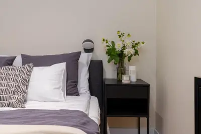 a bedroom with a bed with a vase of flowers on a night stand at Cozy Corner by Cozyplace in Kraków