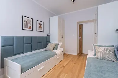 two beds in a bedroom with white walls and wood floors at Cozy Corner by Cozyplace in Kraków