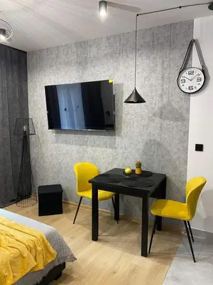 a dining room with a black table and yellow chairs at St. Cross Apartment in Kraków