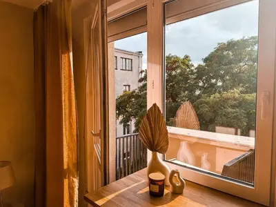 a vase sitting on a table next to a window at Sunset Stories Old Town Apartment in Kraków
