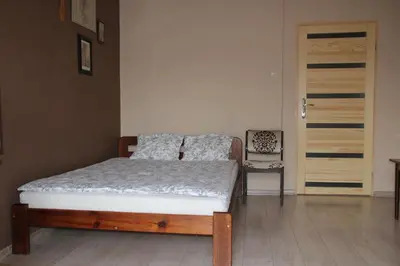 a bedroom with a bed and a chair next to a door at Apartment Widok in Kraków