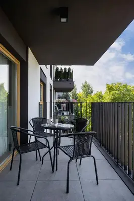 a patio with a table and chairs on a balcony at Tauron Arena Crakow Apartment with Parking by Noclegi Renters in Kraków