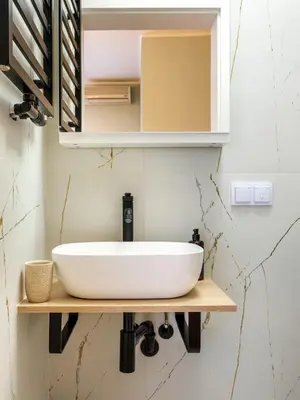 a bathroom with a white sink on a wooden shelf at Tyzenhauz Apartments Pawia Street in Kraków