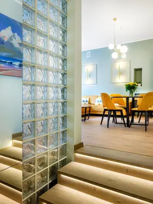 a wall of glass blocks separates a dining room from a living room at Tyzenhauz Apartments Pawia Street in Kraków