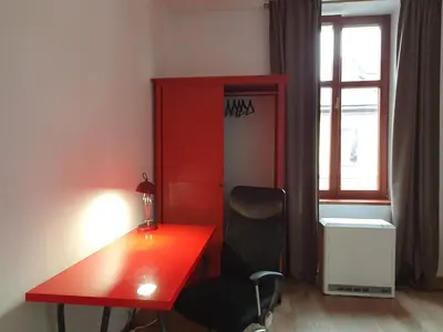 a red desk and a chair in a room with a window at F-3 Kraków Rynek-Wawel O&P ApartFamily in Kraków