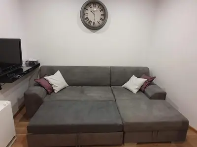 a couch in a living room with a clock on the wall at F-3 Kraków Rynek-Wawel O&P ApartFamily in Kraków