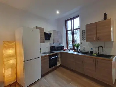 a kitchen with a white refrigerator and wooden cabinets at F-3 Kraków Rynek-Wawel O&P ApartFamily in Kraków