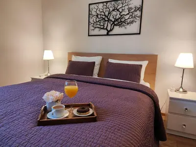 a bed with a tray of food and a glass of orange juice at F-3 Kraków Rynek-Wawel O&P ApartFamily in Kraków