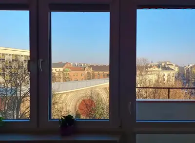 a window with three views of a city through it at Balcony Studio Krakow City Center & Old Town in Kraków