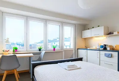 a bedroom with a bed and a kitchen with windows at Balcony Studio Krakow City Center & Old Town in Kraków