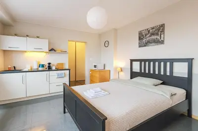 a bedroom with a large bed and a kitchen at Balcony Studio Krakow City Center & Old Town in Kraków