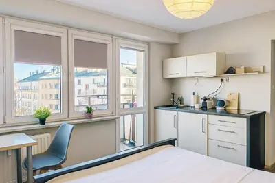 a kitchen with a bed and a table and some windows at Balcony Studio Krakow City Center & Old Town in Kraków