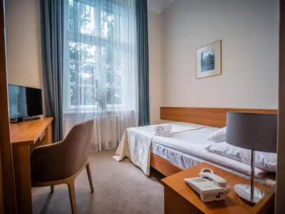 a hotel room with a bed and a desk and a window at Dom Profesorski im. Stanisława Pigonia in Kraków