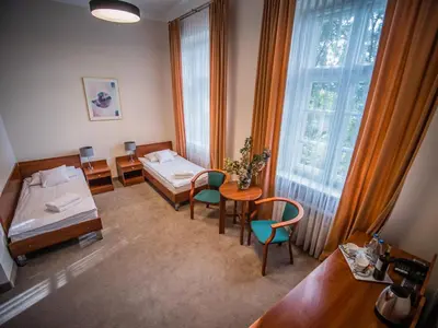 a hospital room with two beds and a table and chairs at Dom Profesorski im. Stanisława Pigonia in Kraków