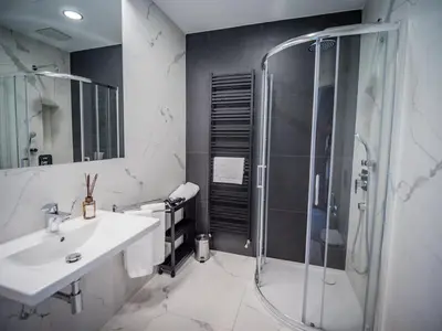 a white bathroom with a shower and a sink at Dom Profesorski im. Stanisława Pigonia in Kraków