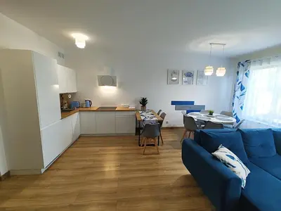 a living room with a blue couch and a kitchen at Domek Niebieskie Marzenie in Chrzanów