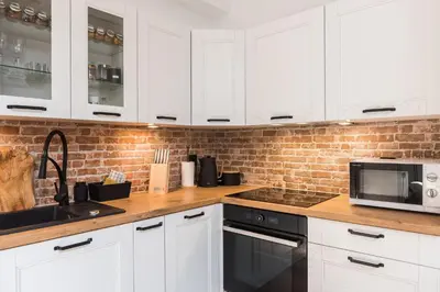 a kitchen with white cabinets and a sink and a microwave at WAWELOFT APARTMENT in Kraków