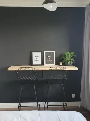 a desk with two stools in front of a wall at Apartamenty Cześć Kraków in Kraków