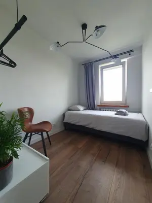 a bedroom with a bed and a chair and a window at Apartamenty Cześć Kraków in Kraków