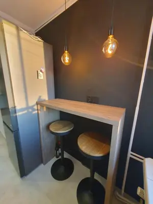 a bar with two stools under a counter with lights at Apartamenty Cześć Kraków in Kraków