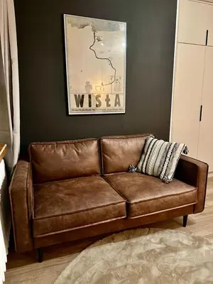 a brown leather couch sitting in a living room at Apartamenty Cześć Kraków in Kraków