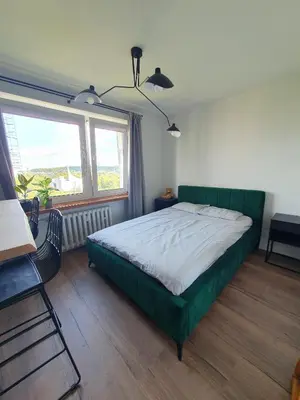 a bedroom with a green bed and a window at Apartamenty Cześć Kraków in Kraków