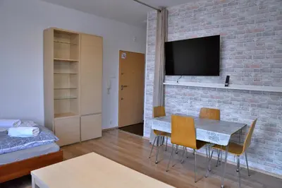 a living room with a dining room table and a brick wall at Ring Apartments - Kraków in Kraków