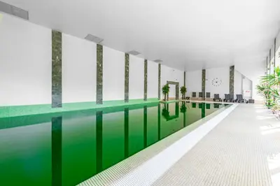 an indoor pool with green water in a building at Hotel Olivia Medical SPA in Skomielna Czarna