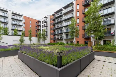 a garden with purple flowers in front of buildings at Beautiful Apartment Klimeckiego with balcony by Noclegi Renters in Kraków