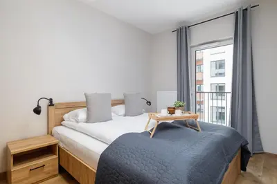 a bedroom with a bed with a table and a window at Modern Apartment Podgorze with Parking by Noclegi Renters in Kraków
