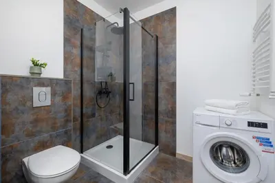 a bathroom with a toilet and a washing machine at Modern Apartment Podgorze with Parking by Noclegi Renters in Kraków