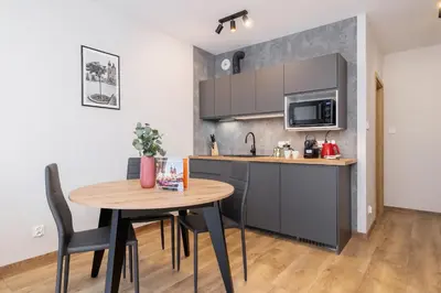 a kitchen and dining room with a table and chairs at Modern Apartment Podgorze with Parking by Noclegi Renters in Kraków