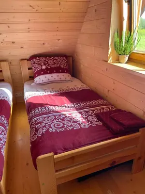 a small bed in a log cabin with a window at Pod Gwiazdami in Dąbrówka