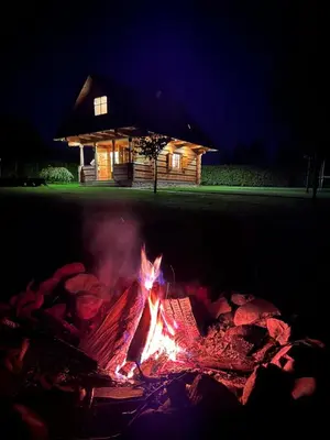 a fire in front of a log cabin at night at Pod Gwiazdami in Dąbrówka
