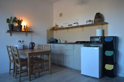 a kitchen with a wooden table and a table and a refrigerator at Parrot's Apartment in Kraków