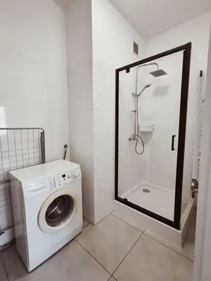a washing machine in a bathroom with a shower at Parrot's Apartment in Kraków