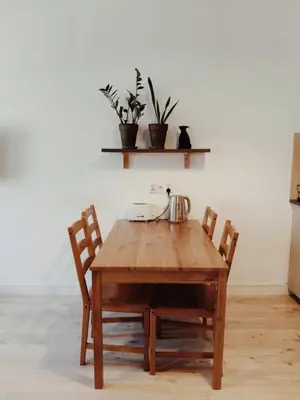 a wooden table with two chairs and a tea kettle on it at Parrot's Apartment in Kraków
